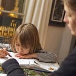 Enfant, eleve de CP, avec sa nounou a la maison. Devoirs le soir apres l'ecole education